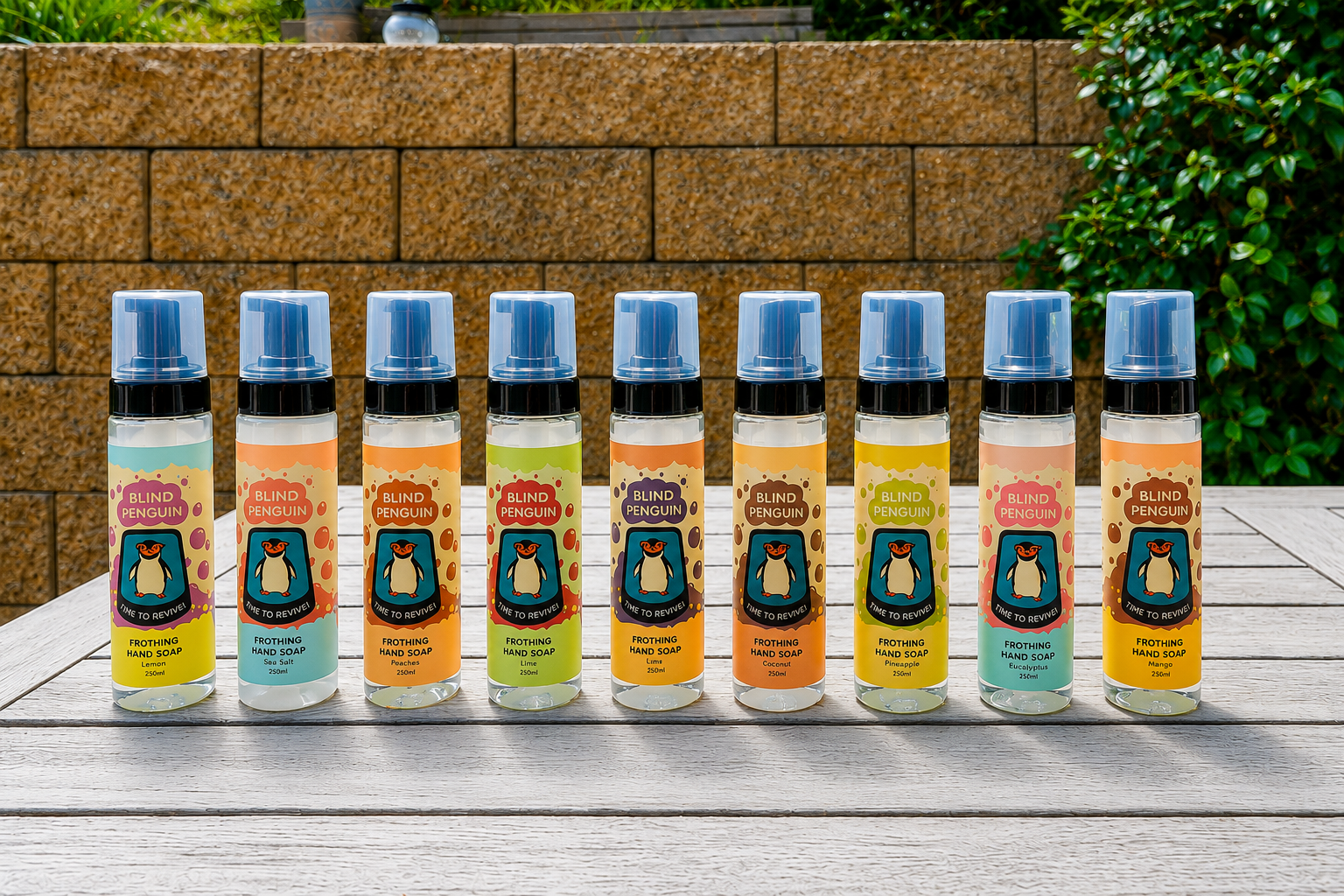 Row of spray bottles with colorful labels on a wooden surface outdoors.
