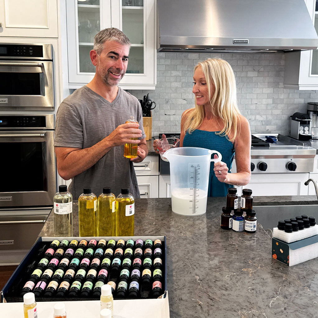 Man and woman in a kitchen with various bottles and containers on the counter