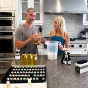 Man and woman in a kitchen with various bottles and containers on the counter